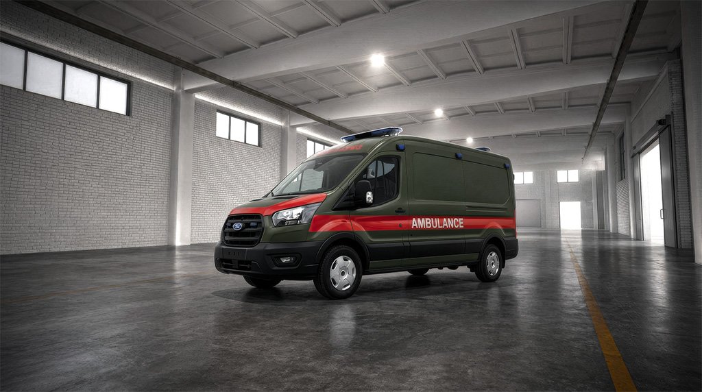 A green and red ambulance parked in a large warehouse with a concrete floor and brick walls.
