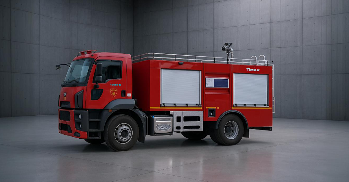 A red fire truck parked in a gray room with concrete walls and floors, featuring a large front window and a ladder on top.