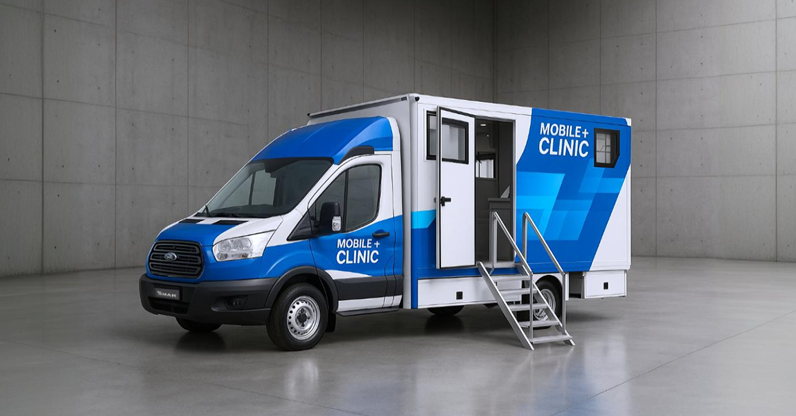 A white and blue mobile clinic van is parked in a gray concrete room, featuring a large door with stairs leading up to it.