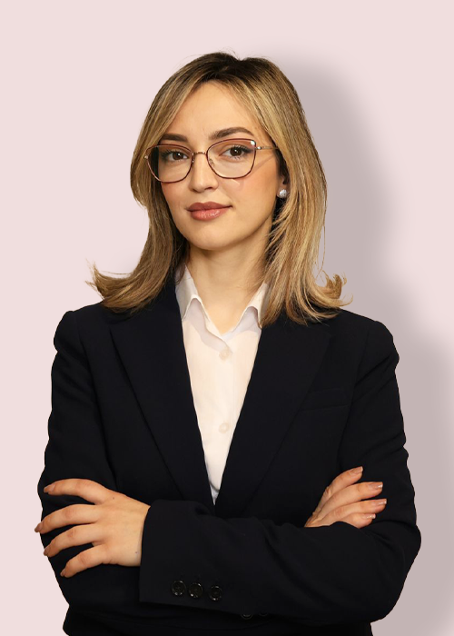 There are no vehicles in this image, which features a woman in a black suit and white shirt standing against a plain background.