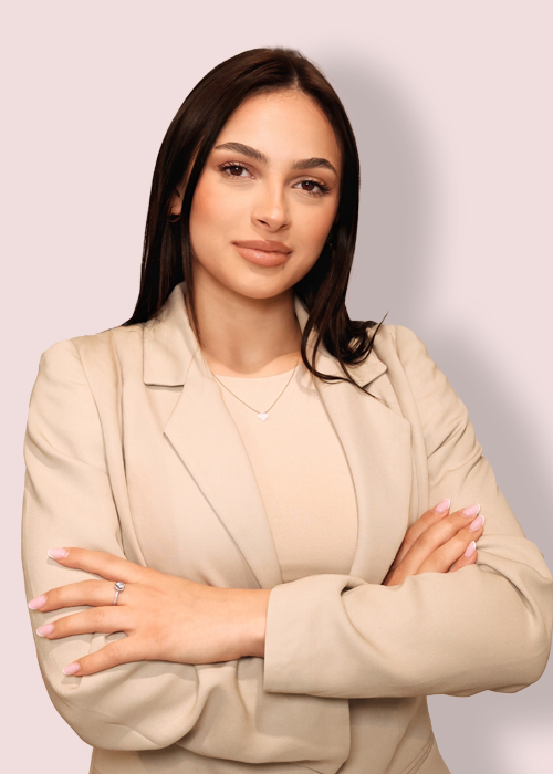 A woman in a beige suit posing with her arms crossed, exuding confidence and professionalism.